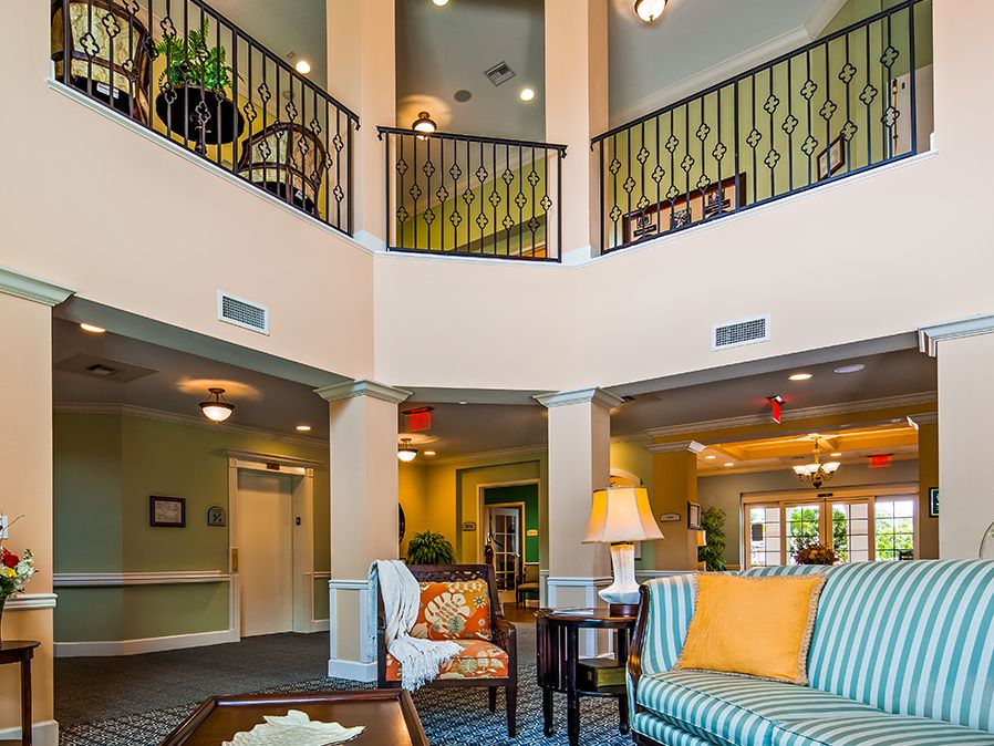 A modern living room with stylish furniture and elegant lighting, featuring a balcony above.