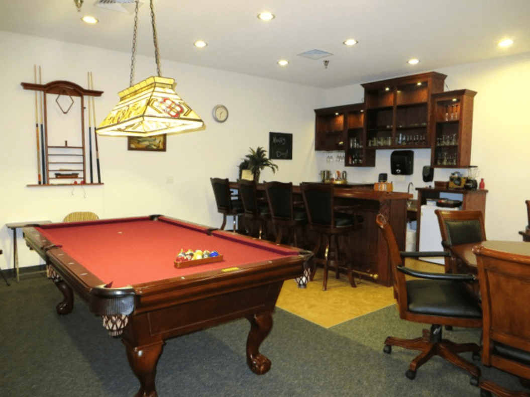 A cozy game room featuring a pool table and a bar area.