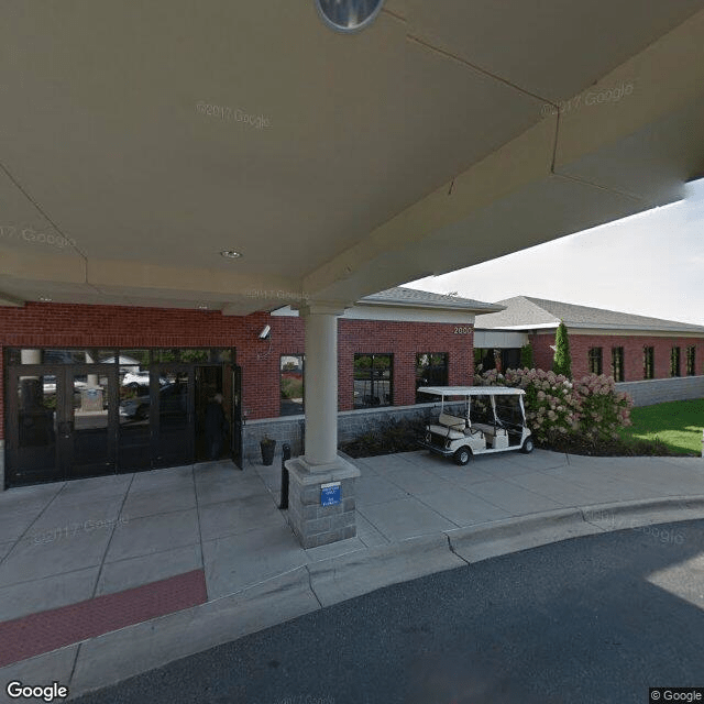 Exterior view of a building entrance with a golf cart parked under a covered walkway.