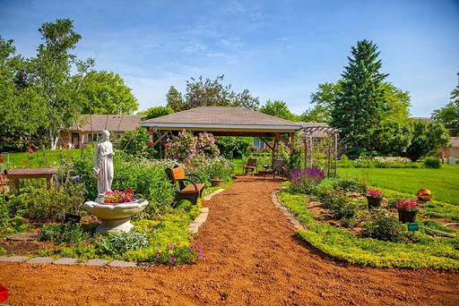 A serene garden pathway surrounded by vibrant flowers and a charming statue, perfect for relaxation.