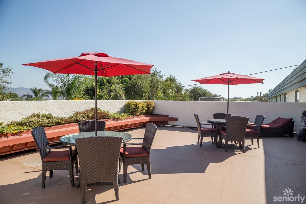 A sunny outdoor patio with tables and red umbrellas.