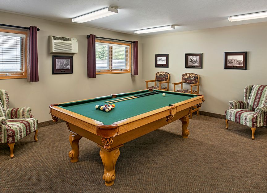 A cozy game room featuring a billiards table, chairs, and framed wall art.