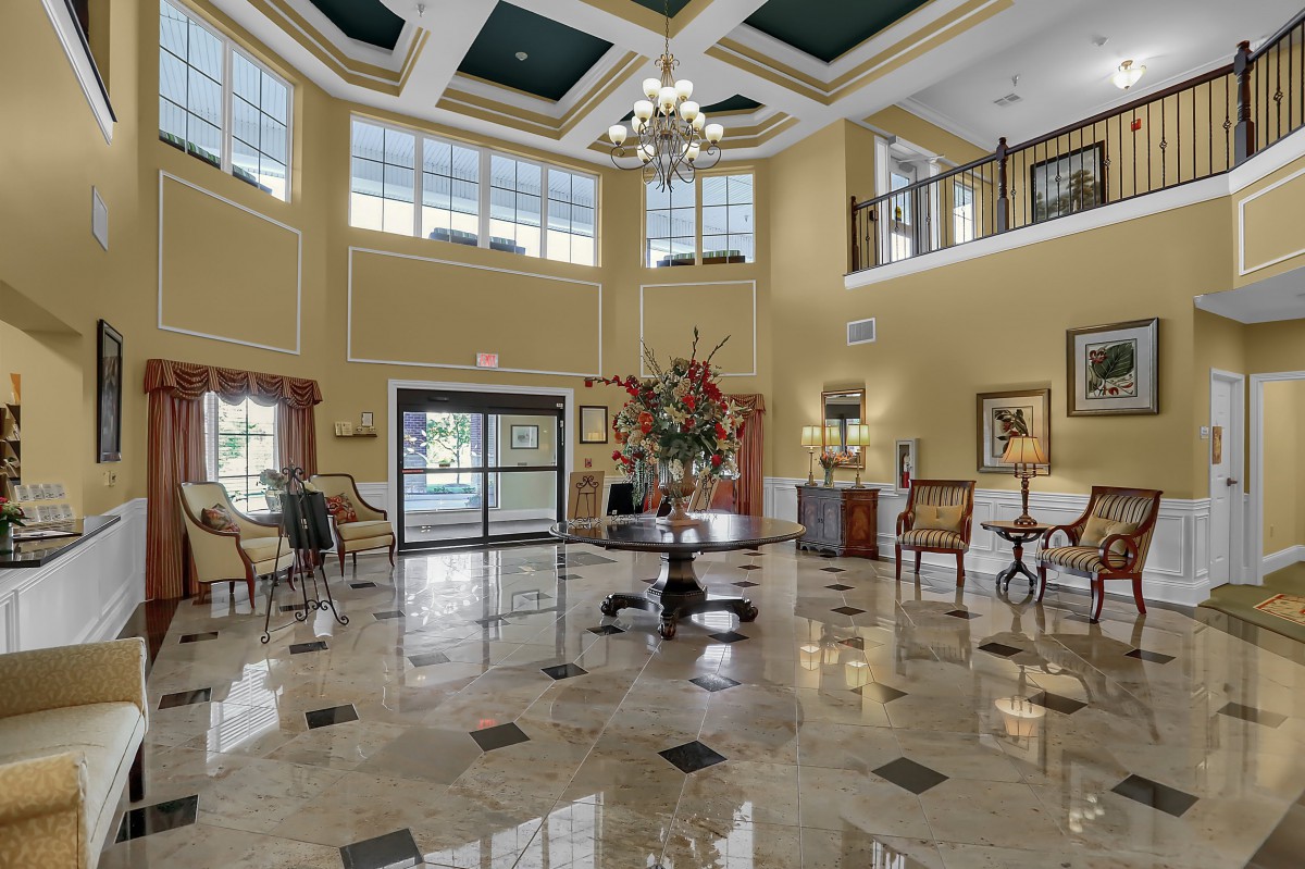A spacious and elegantly decorated lobby with large windows, a chandelier, and a polished marble floor.