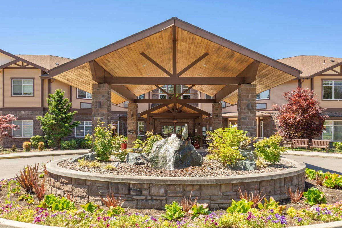 A beautifully landscaped entrance to a modern building with wooden and stone architectural elements.