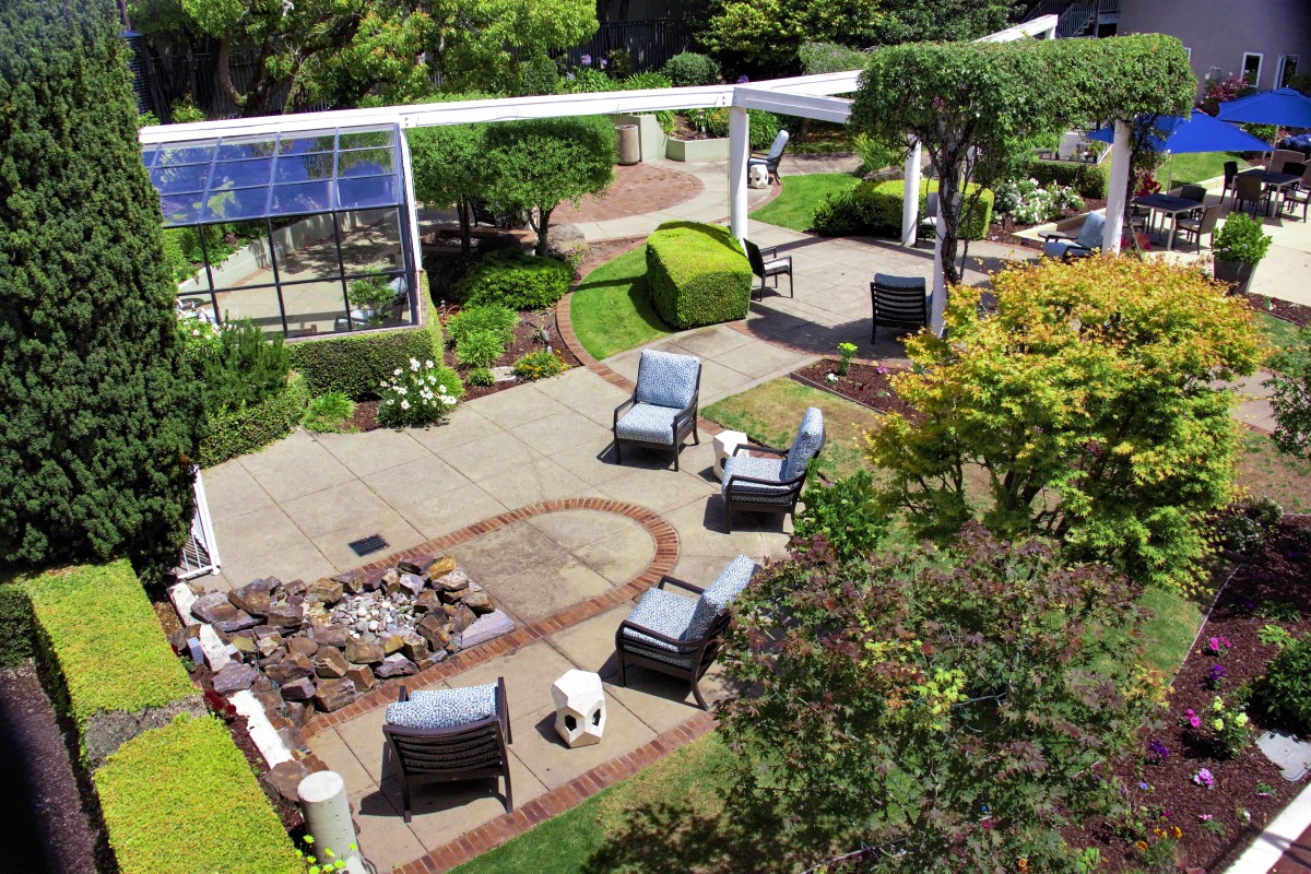 A beautifully landscaped garden with a patio, outdoor seating, and a fire pit area.