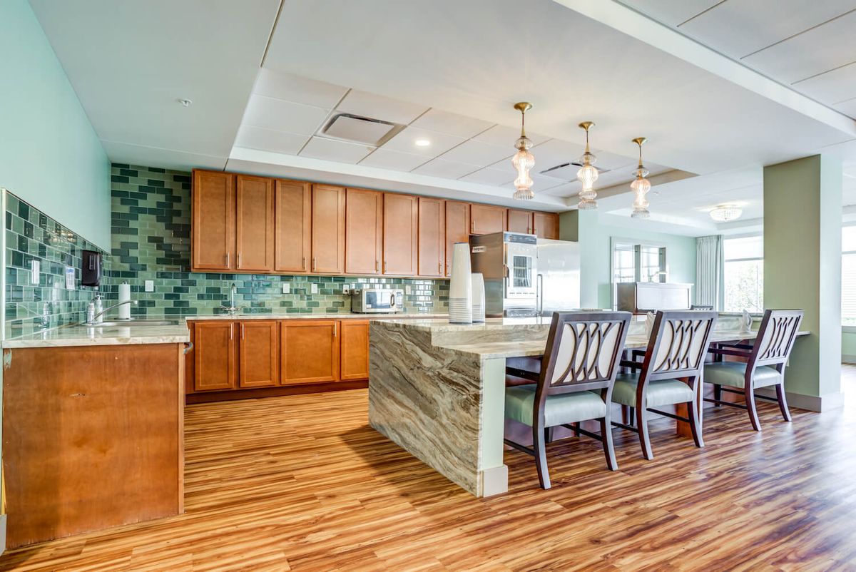 A modern kitchen with a large island, wooden cabinets, and stylish pendant lights.