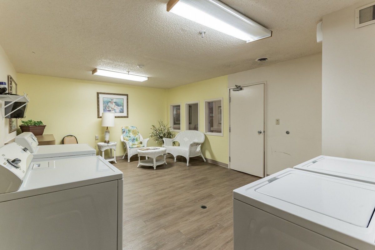 A well-lit laundry room with washing machines and a cozy seating area.