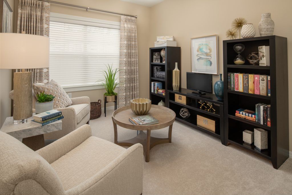 A cozy living room with modern decor, featuring comfortable seating and a well-organized bookshelf.