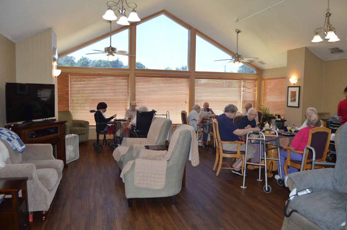 A cozy living room with various seating and a group of people relaxing and engaging in activities.