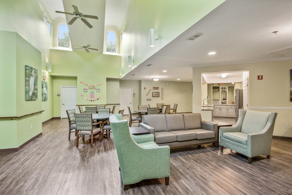 A modern living room with green walls, featuring comfortable seating and dining areas.