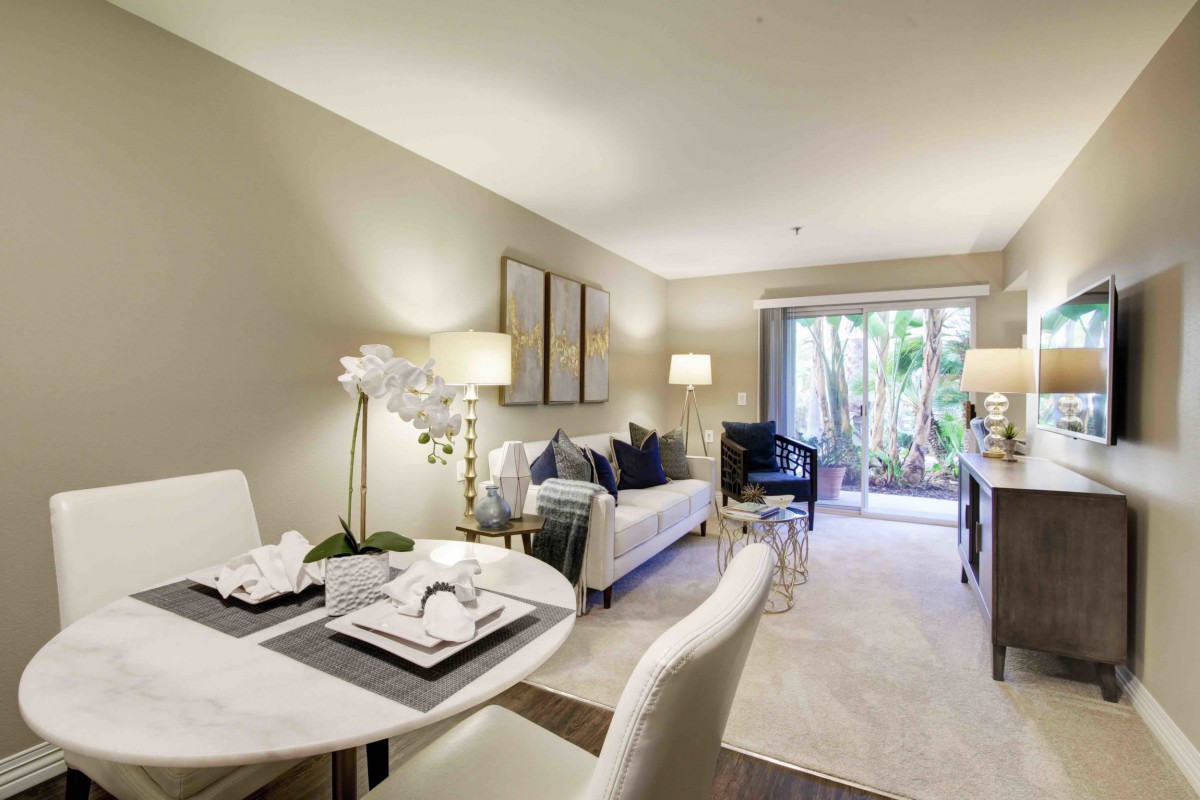 A modern living room with a dining area, featuring elegant furniture and abundant natural light.
