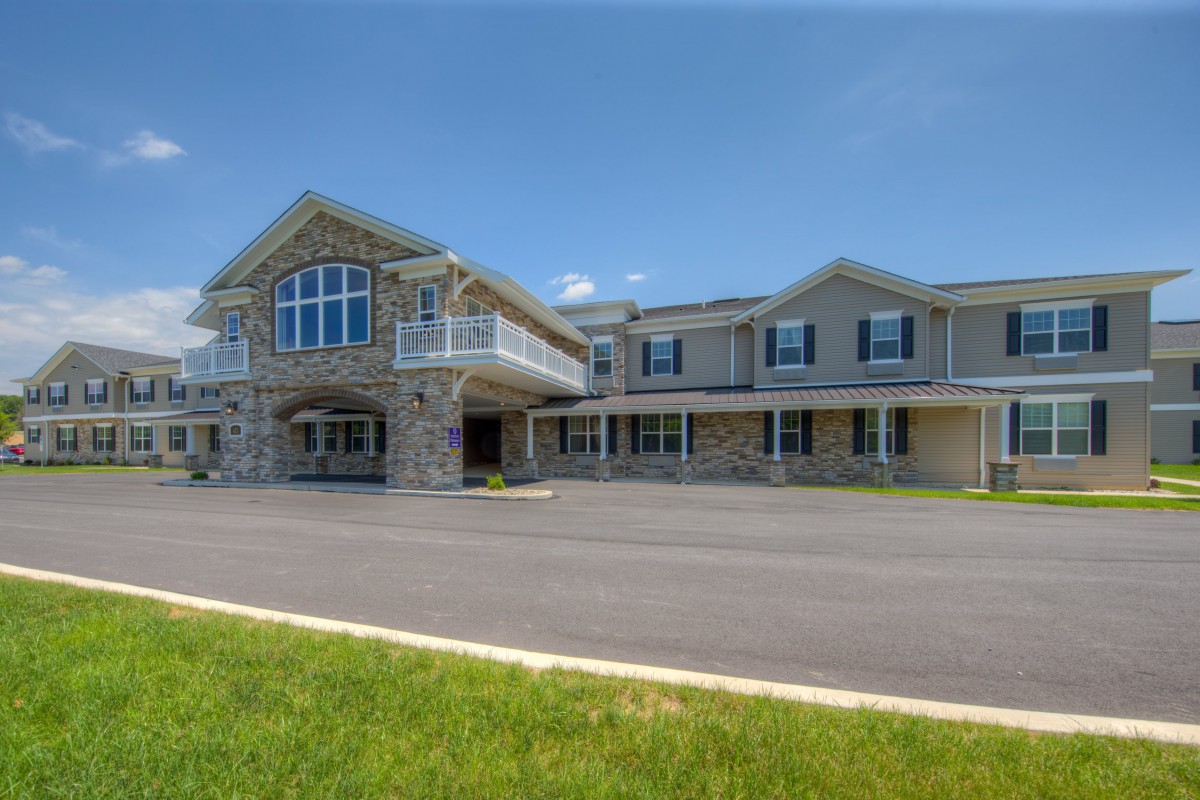 A large two-story house with a wide driveway and manicured lawn.