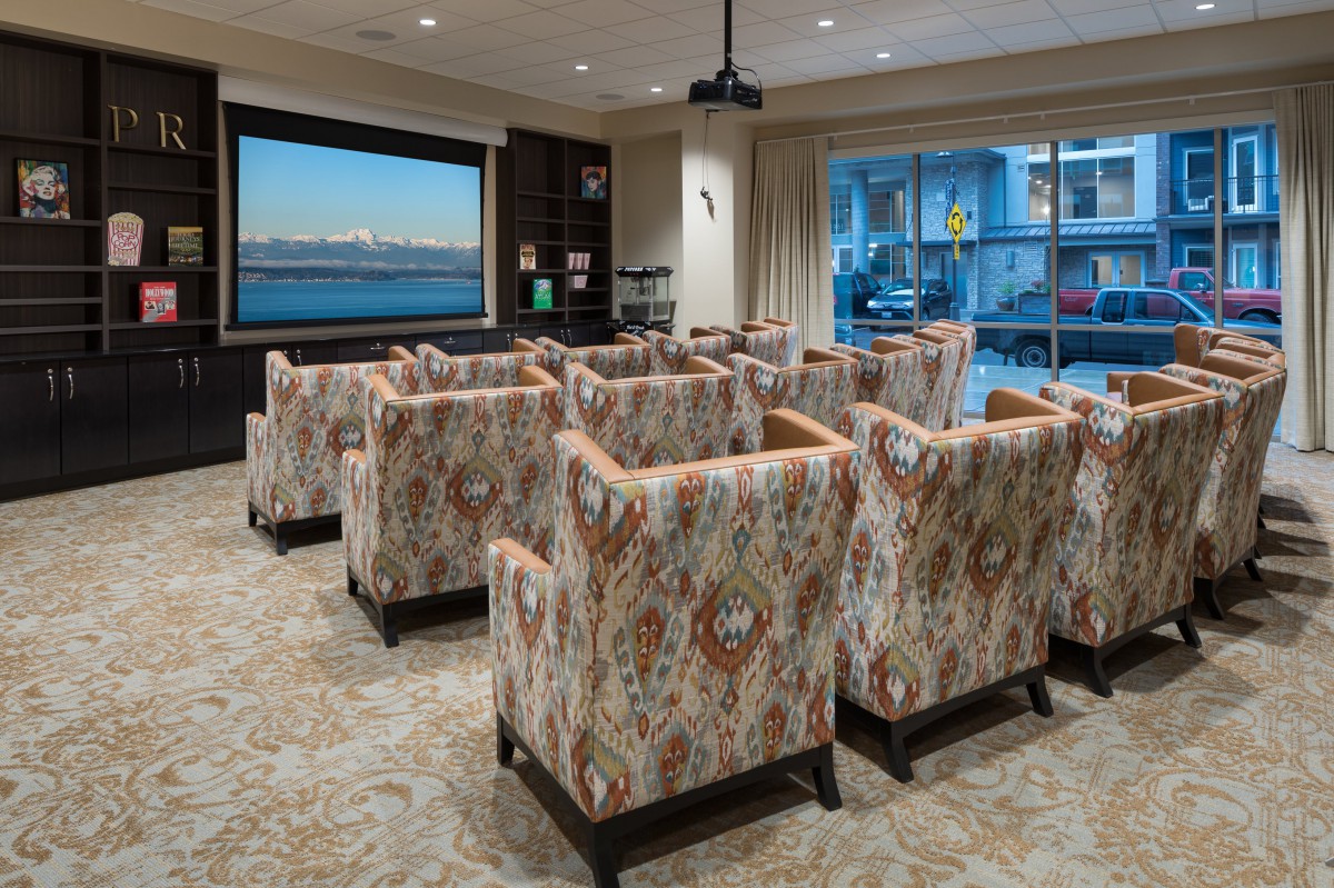 A cozy home theater with patterned armchairs facing a large projector screen.