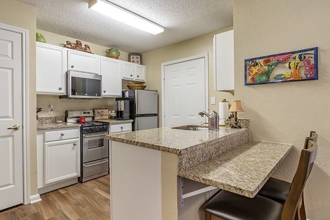 A modern kitchen with white cabinets, granite countertops, and stainless steel appliances.