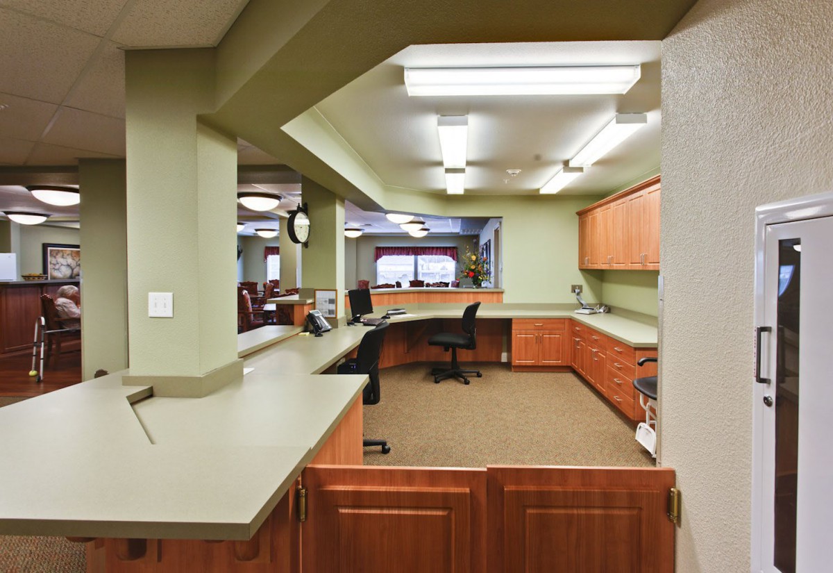 A modern office reception area with desks and chairs.