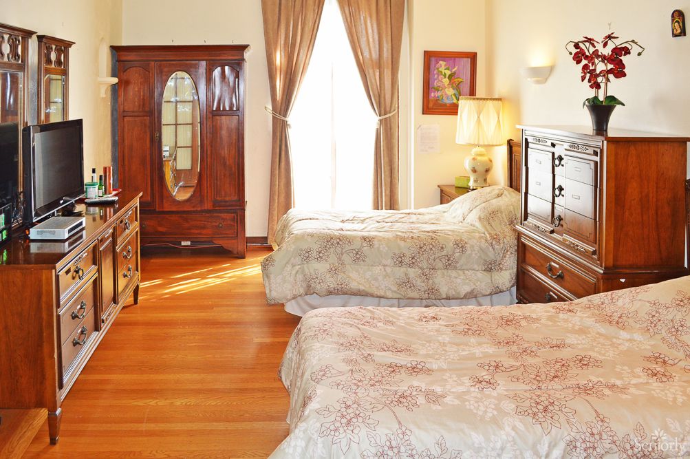 A cozy bedroom with vintage furniture, featuring two beds and an armoire.