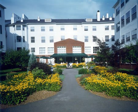 A building with a beautifully landscaped garden and pathway lined with vibrant flowers.