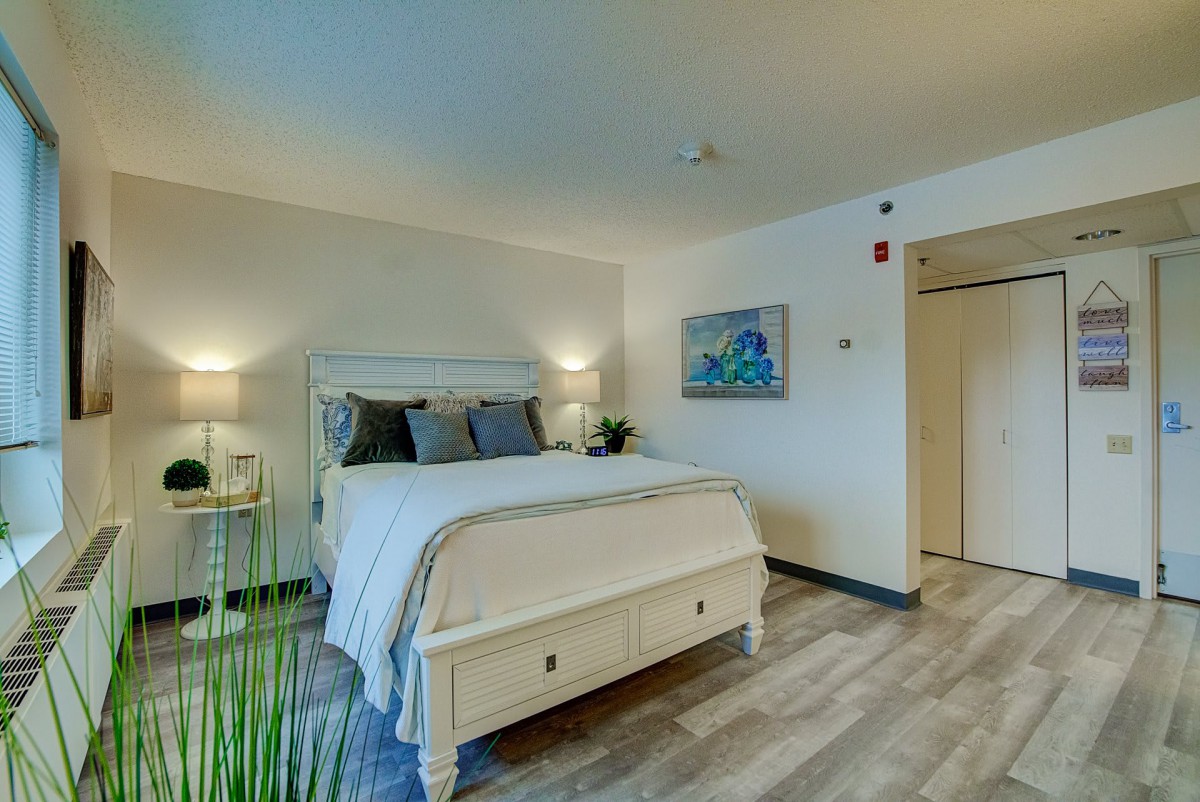 A modern, minimalist bedroom featuring a neatly made bed, nightstands with lamps, and simple decor.