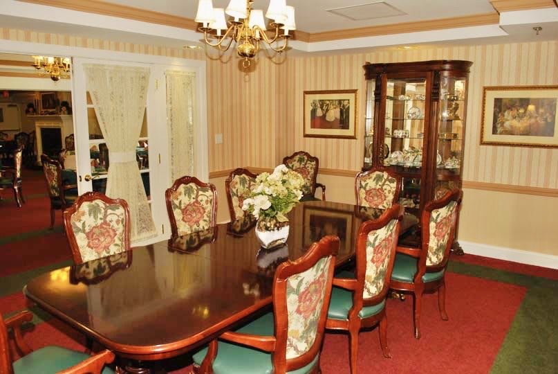Elegant dining room with a classic design featuring a large wooden table, ornate chairs, and a chandelier.