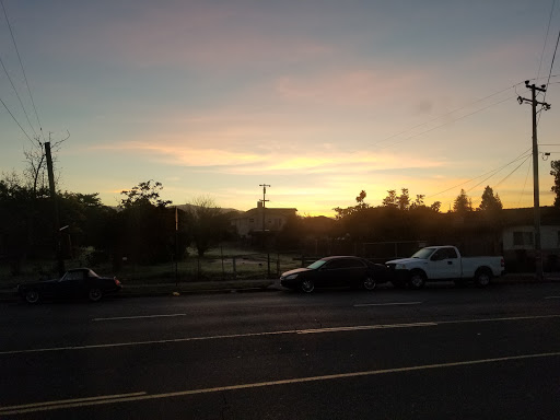 A serene sunset casts a warm glow over the parked cars and landscape.