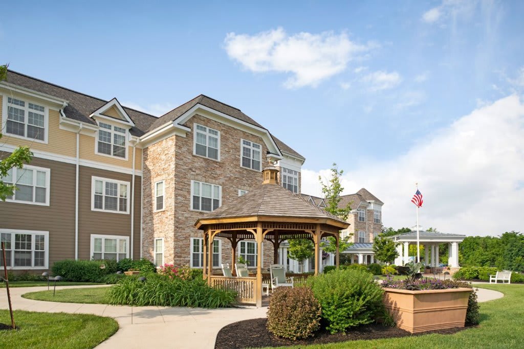 A modern building with a charming gazebo surrounded by lush greenery and a clear blue sky.