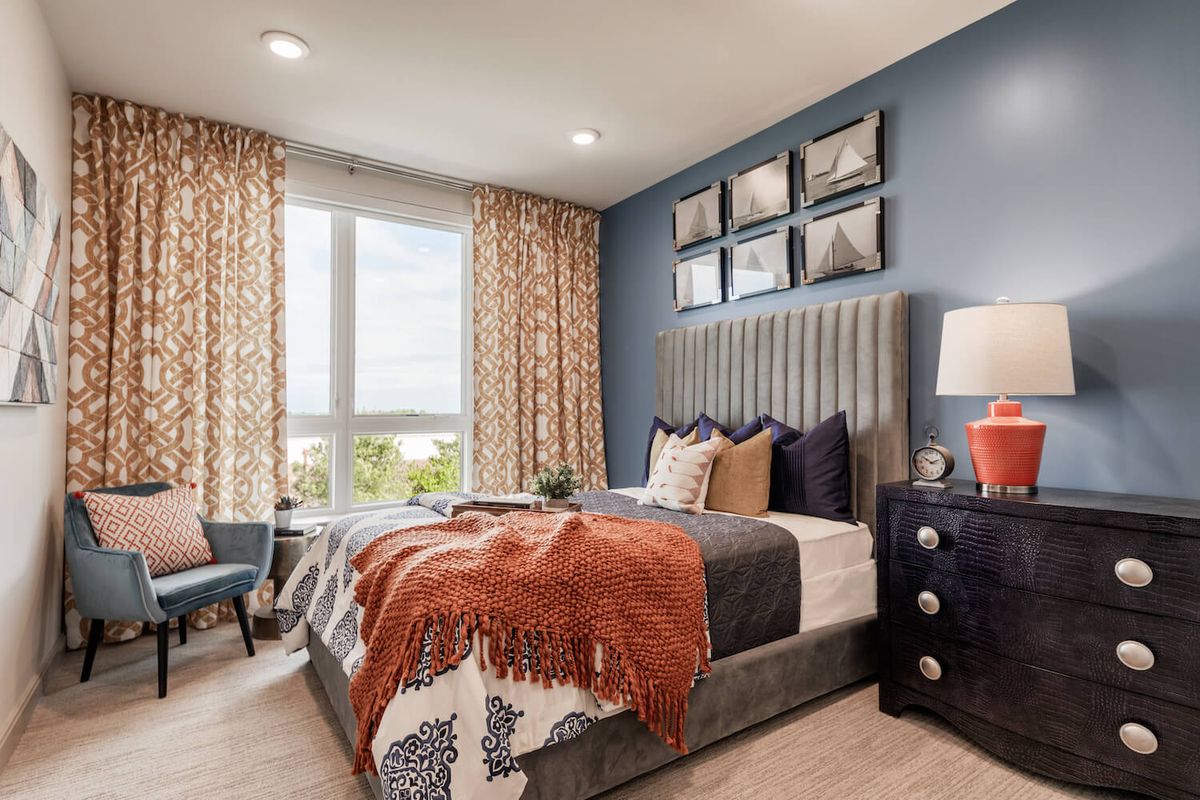 A modern, stylish bedroom with a large bed, decorative pillows, and contemporary artwork on the wall.