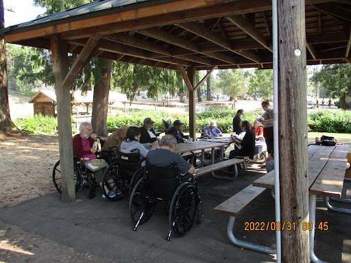A group of people enjoying a social gathering under a wooden shelter.