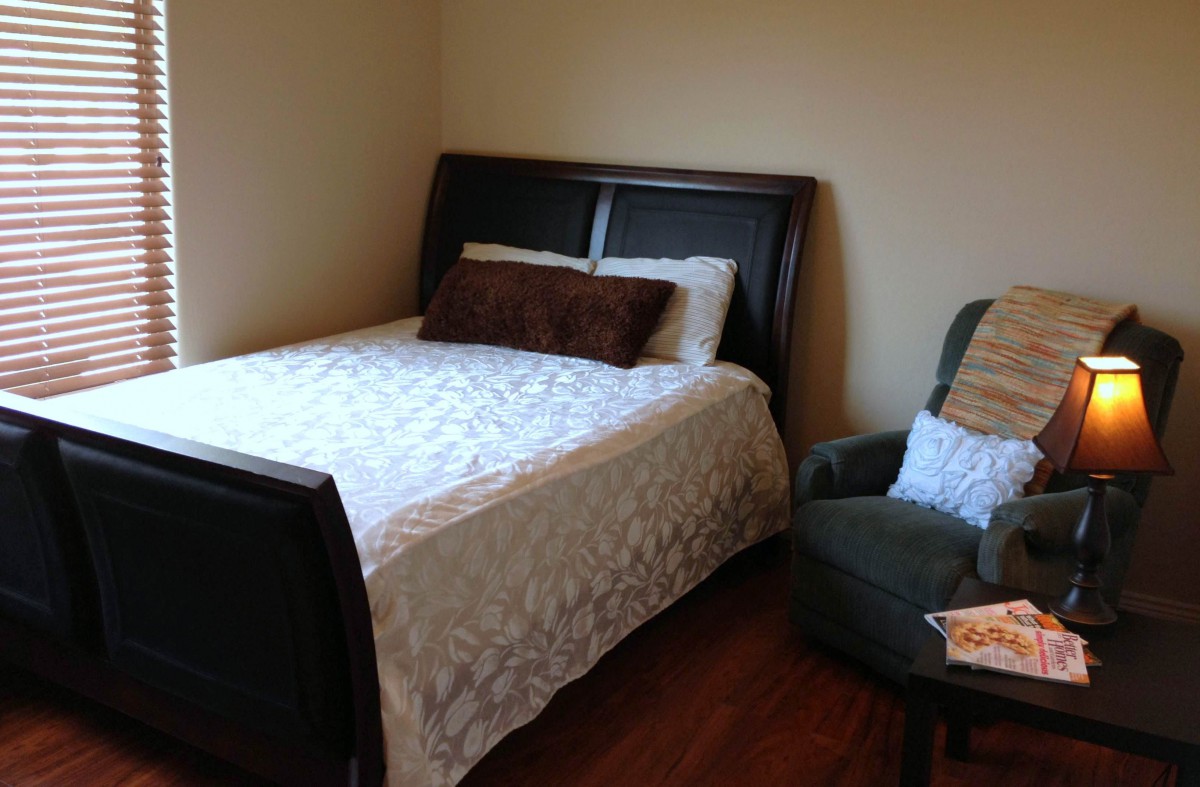 A cozy bedroom with a bed and a chair.
