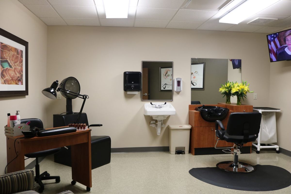 Interior view of a hair salon with chairs, a sink, and flowers.