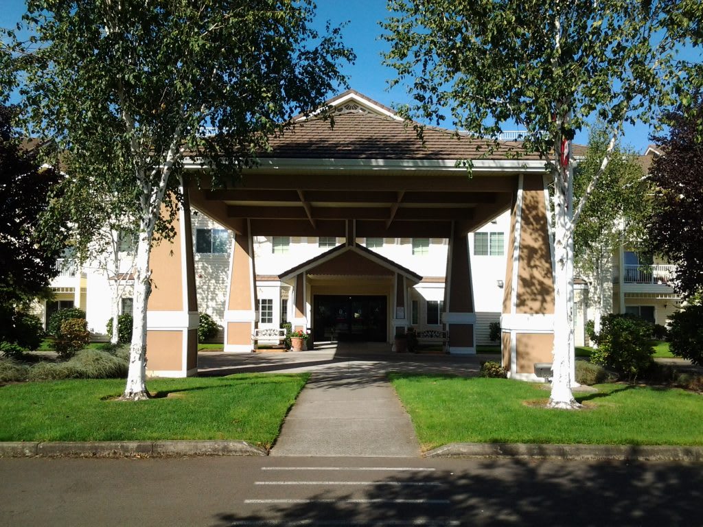 A residential building entrance with a covered pathway and surrounding trees.