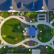 Aerial view of a landscaped garden with winding pathways and adjacent buildings.