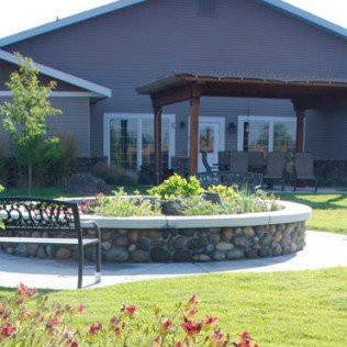 A house with a landscaped garden, featuring a bench and patio.