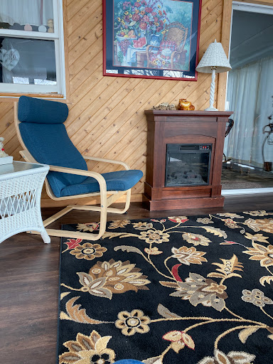 A cozy living room setup featuring a comfortable chair beside a decorative fireplace, complemented by an elegant rug.
