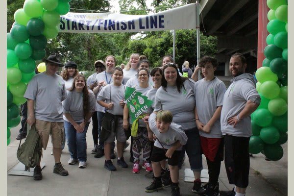 A group of people gathered under a 'START/FINISH LINE' sign, celebrating an event.