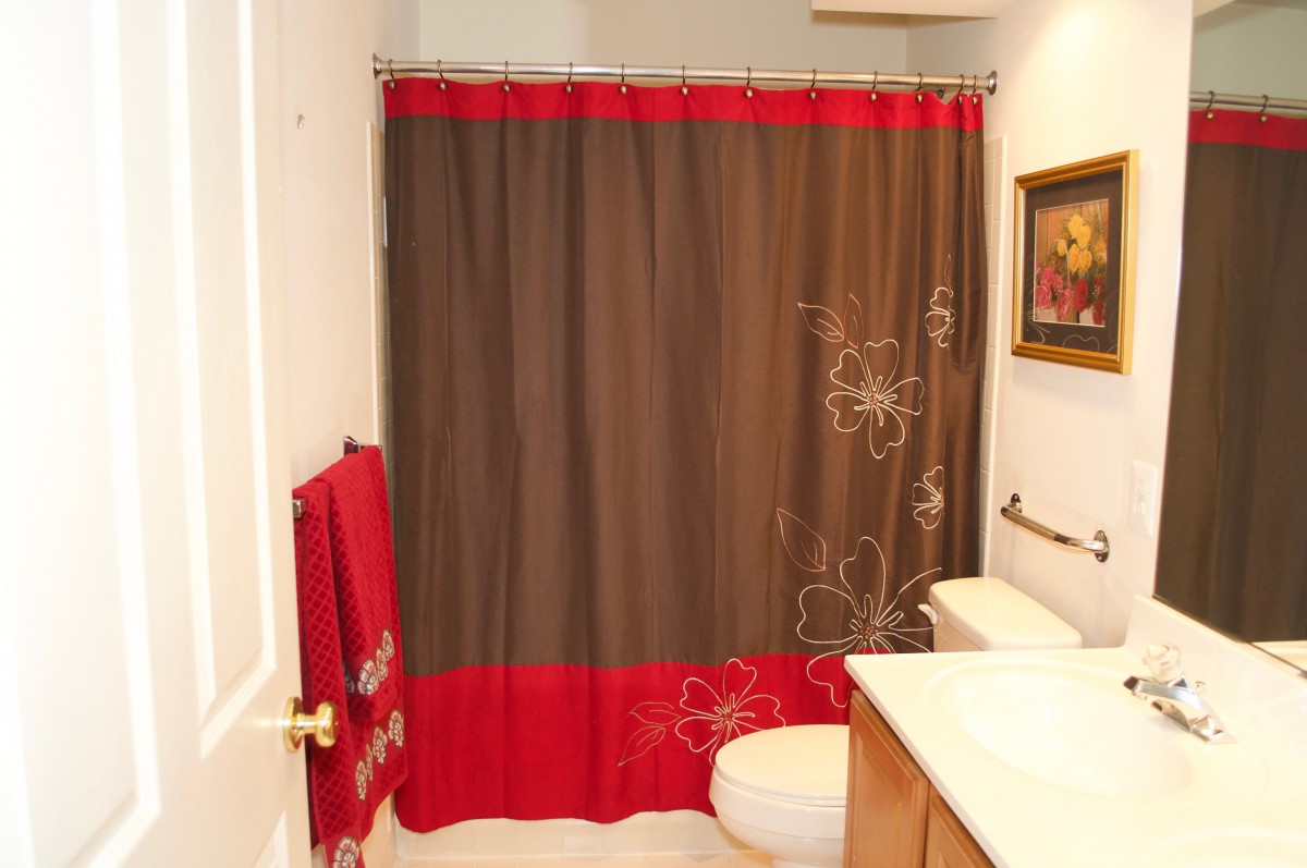 A bathroom featuring a red and brown shower curtain with floral patterns.