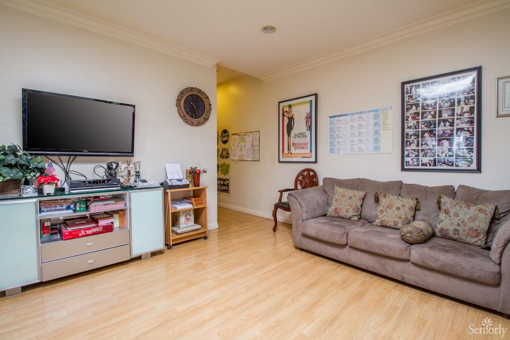 A cozy living room with a sofa, television, and framed artwork on the walls.