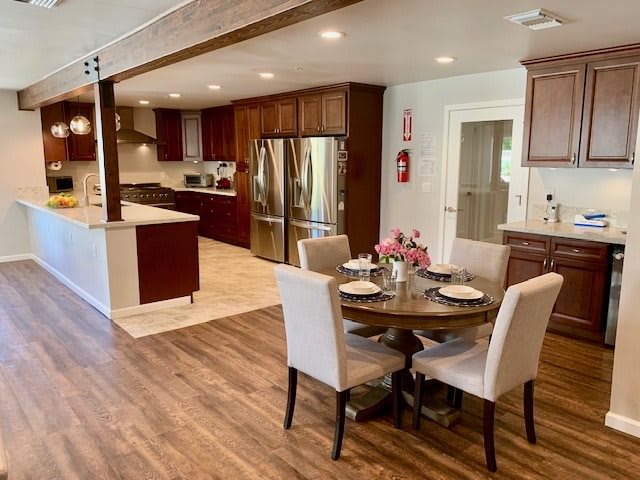 A modern open-plan kitchen and dining area with wood flooring and elegant furniture.