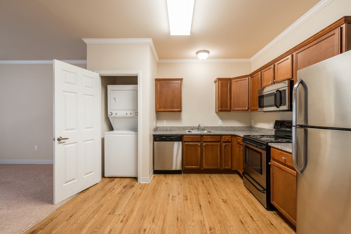 A modern kitchen with wooden cabinets, stainless steel appliances, and a washer-dryer unit.