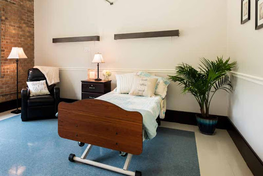 A well-designed patient room featuring a hospital bed, bedside lamp, and a decorative plant.