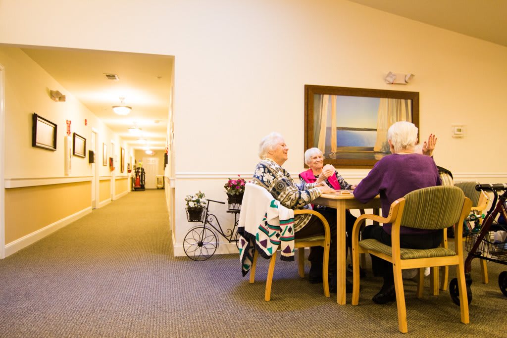 Elderly individuals sitting at a table in a nursing home, engaging in conversation.
