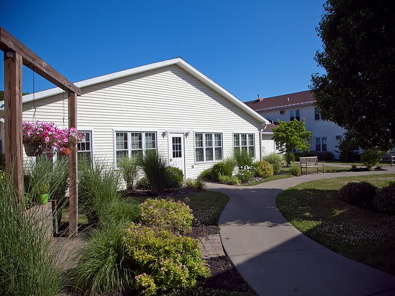 A cozy residential house with a well-maintained garden and pathway on a sunny day.