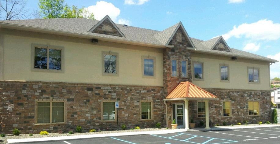 A commercial building with a stone facade and parking lot.