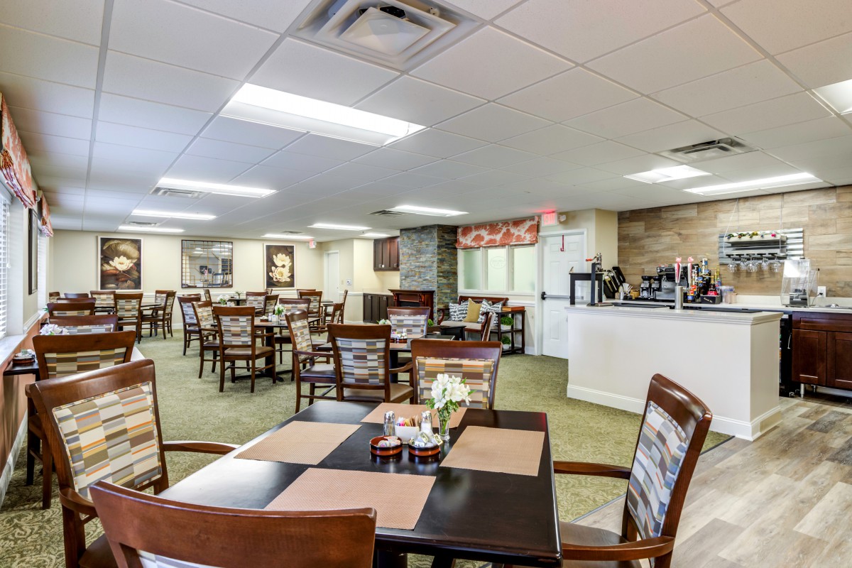 An inviting dining area with multiple tables and chairs neatly arranged, featuring warm decor and bright lighting.