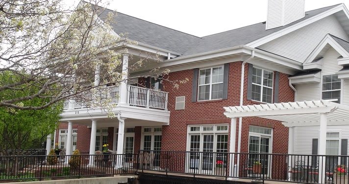 A two-story brick house with a balcony and multiple windows.