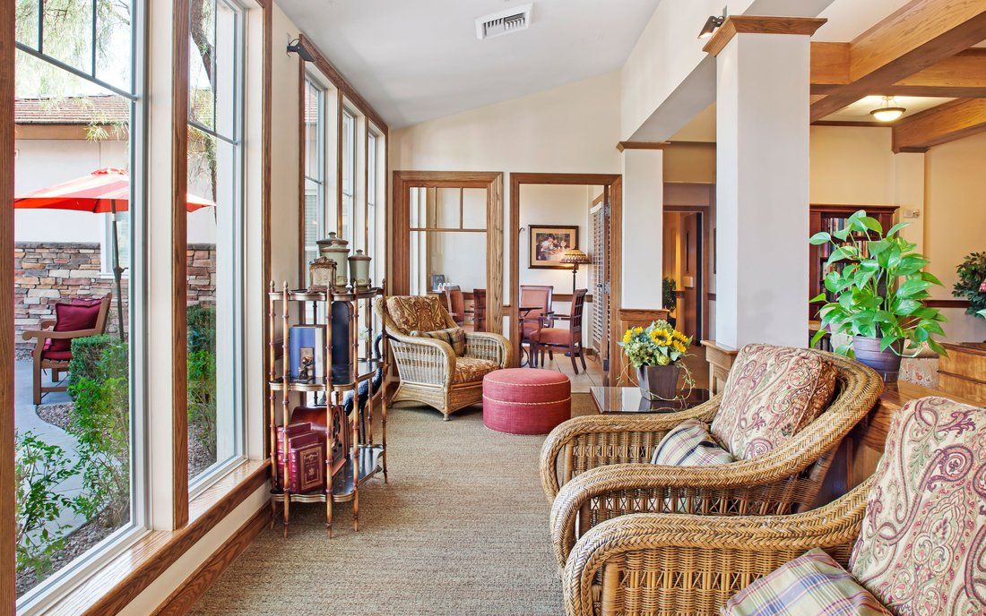 A cozy living room interior featuring natural light from large windows, wicker furniture, and decorative elements.