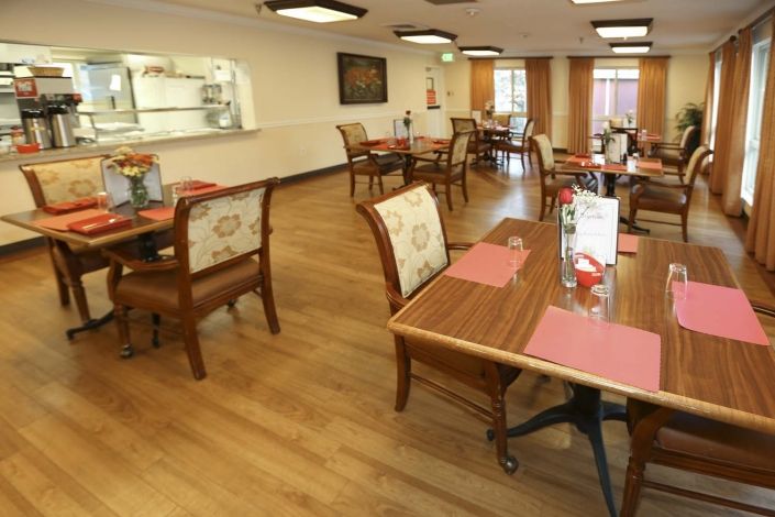 A cozy restaurant dining area with wooden flooring and neatly arranged tables and chairs.