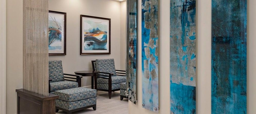 A modern waiting room with abstract artwork and comfortable seating.