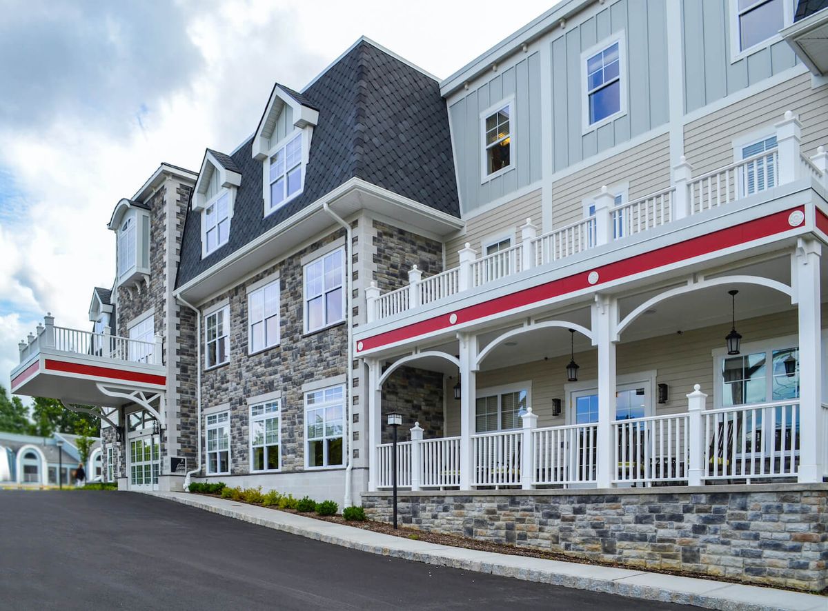 A modern residential building with a stone facade and multiple balconies.