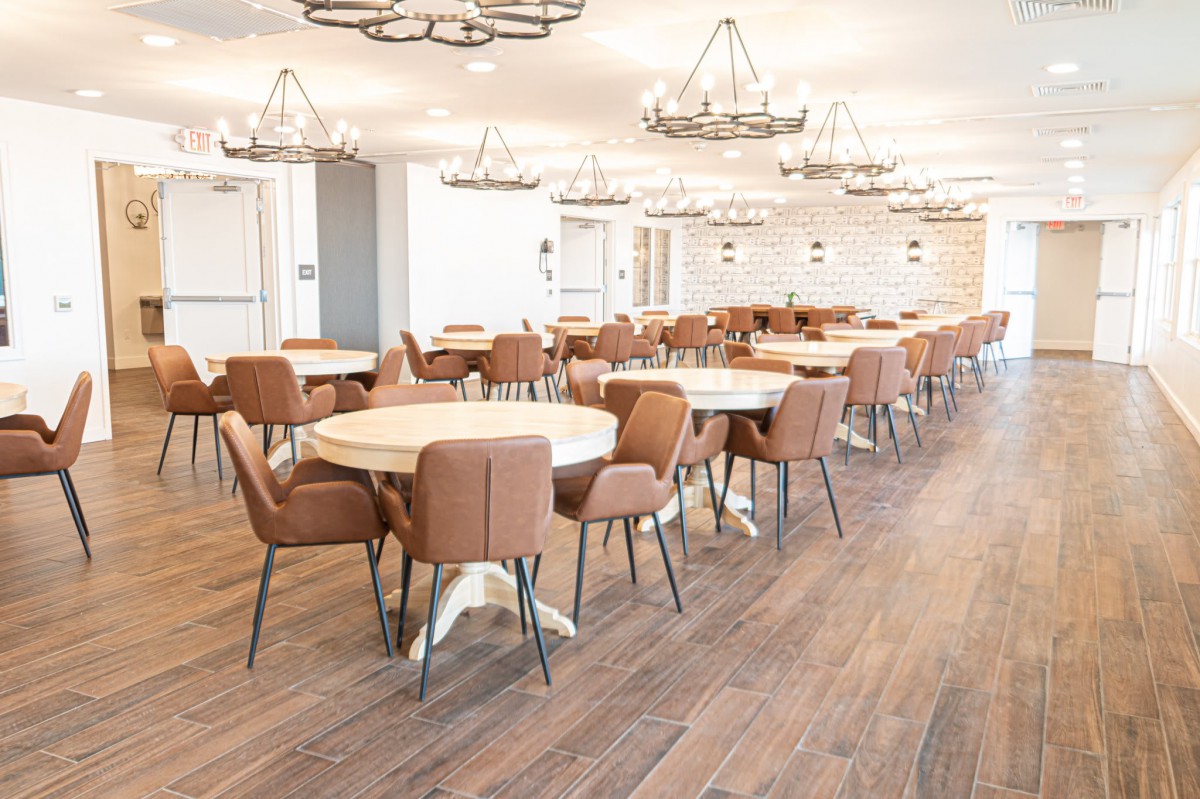 A modern dining area with round tables, upholstered chairs, and elegant chandeliers.