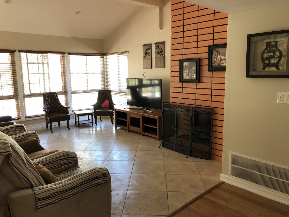 A cozy living room with a television, fireplace, and large windows.